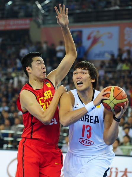 9月24日,中国队球员王治郅(左)防守韩国队球员河升镇.