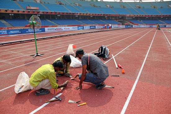 印度新德里,2010英聯邦運動會第3日田徑比賽,工人緊急修復跑道